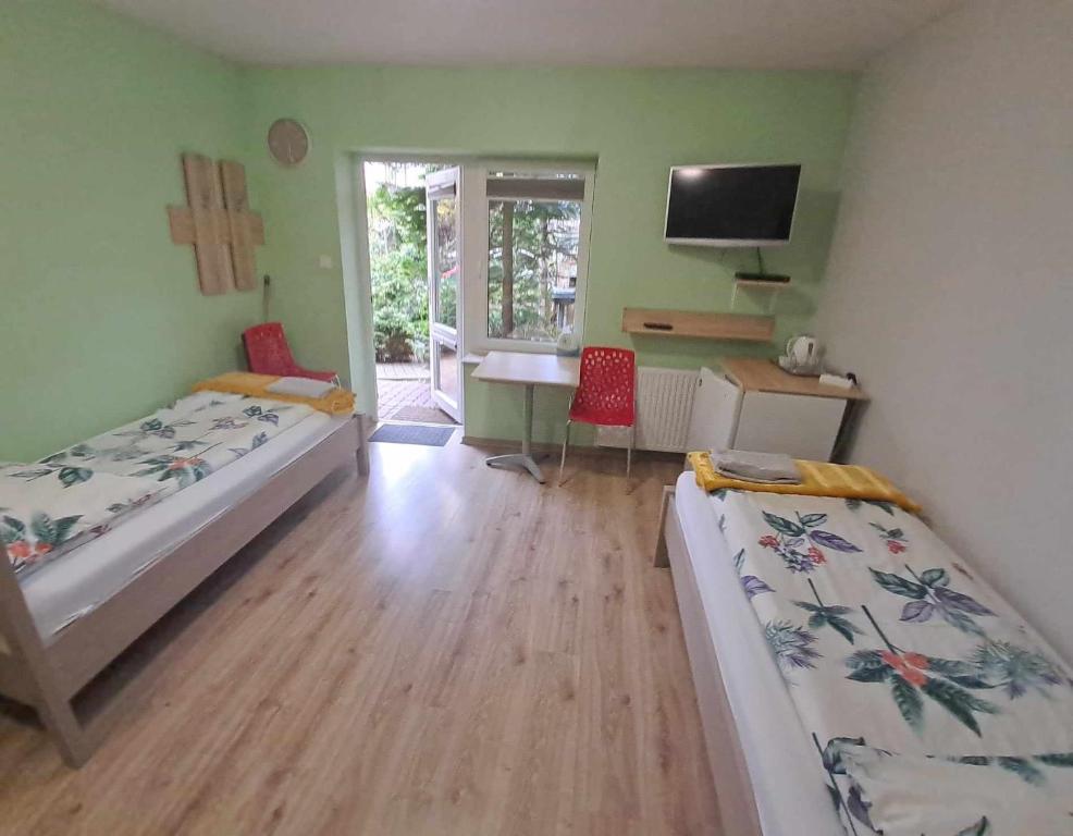 sypialnia z 2 łóżkami, biurkiem i telewizorem w obiekcie noclegi Julia w Kielcach