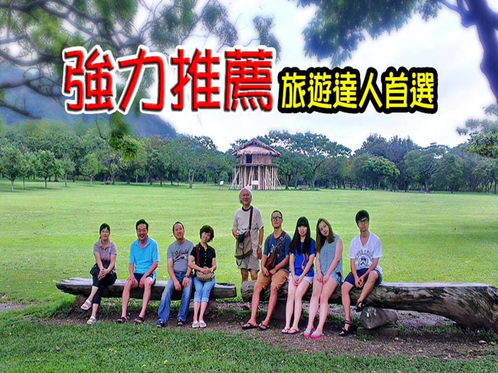 Eine Gruppe von Menschen, die auf einem Logbuch in einem Park sitzen in der Unterkunft 台東卑南公園民宿 in Taitung