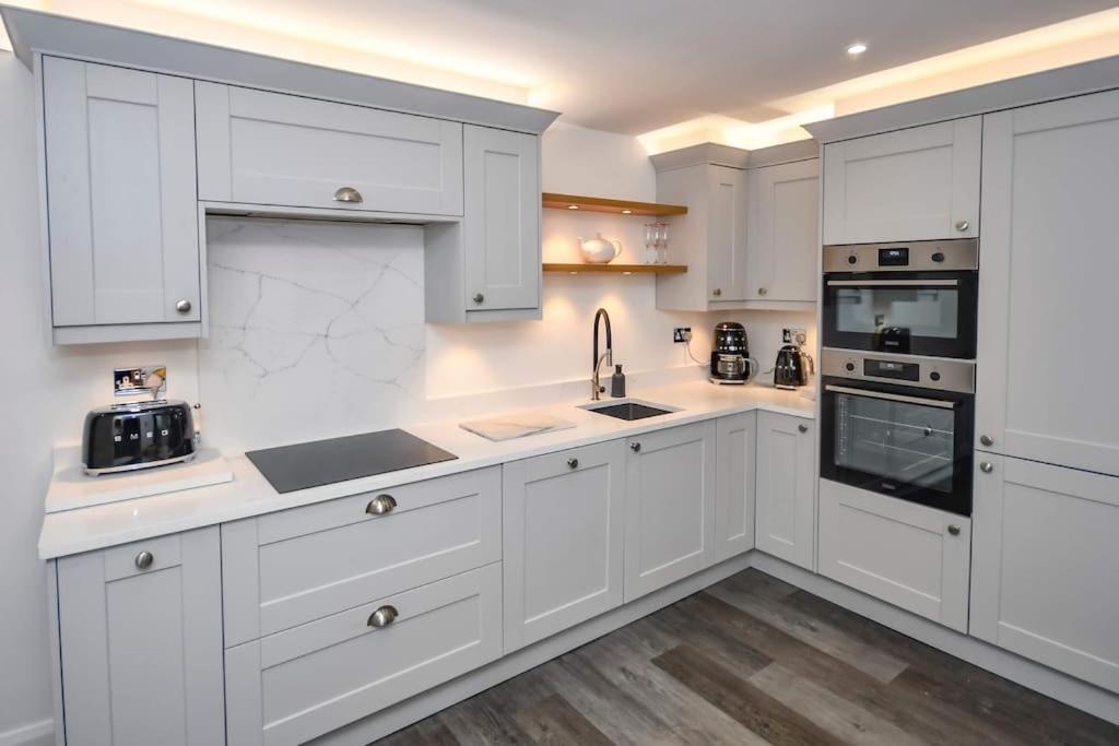 a white kitchen with white cabinets and appliances at The Hideaway - Luxury 2 bedroom ground floor apt in Warkworth