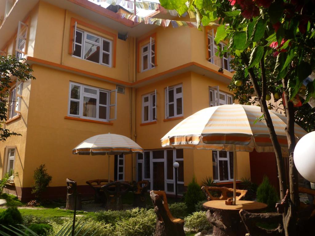ein gelbes Gebäude mit Tischen und Sonnenschirmen davor in der Unterkunft Andes House in Kathmandu