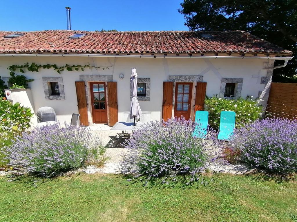 a small white house with blue chairs in the yard at La Vieille Gorce Gîtes in the Vienne in Asnois