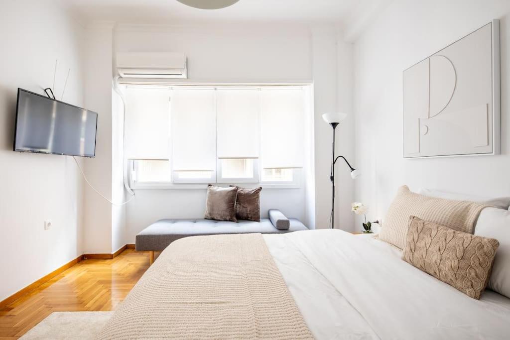 a white bedroom with a bed and a couch at Supreme Aprt Syntagma Kolonaki in Athens