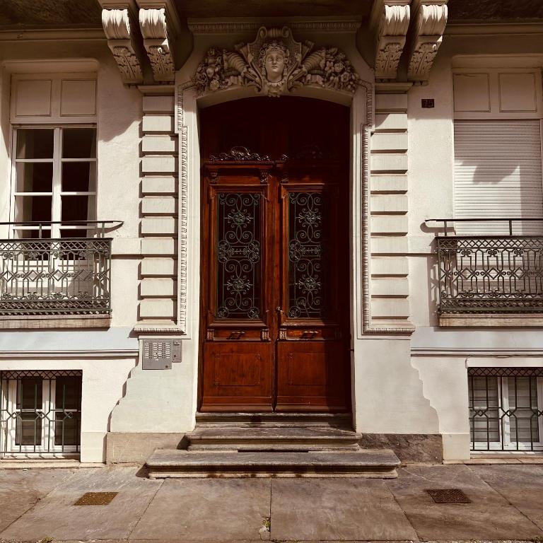 - une grande porte en bois dans un bâtiment blanc dans l'établissement Le NID DES BAINS, à Luchon
