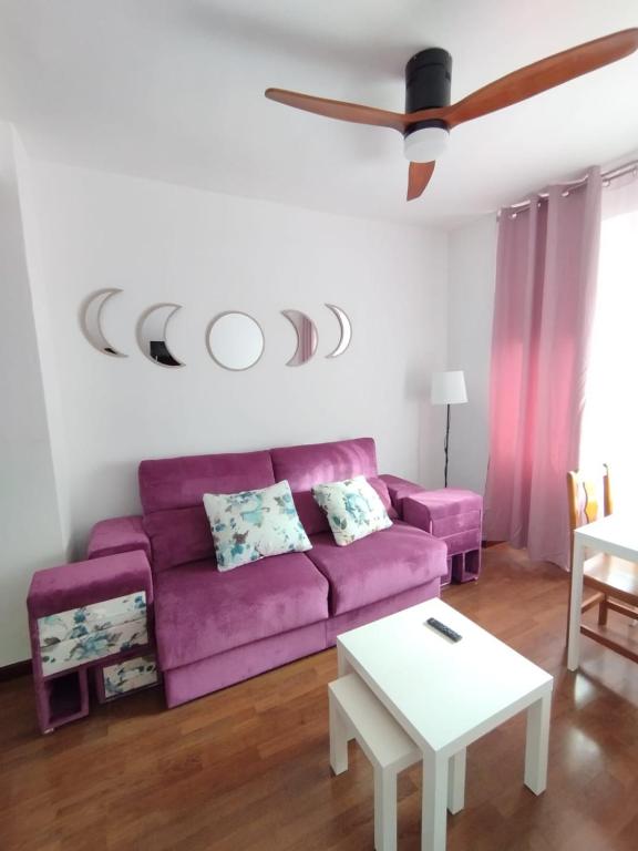 ein Wohnzimmer mit einem lila Sofa und einem Deckenventilator in der Unterkunft Piso luminoso en Madrid Rio in Madrid