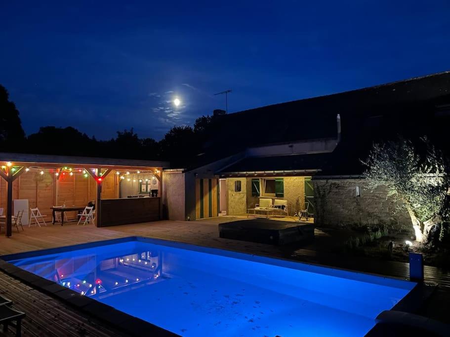 una piscina frente a una casa por la noche en Maison avec piscine et jacuzzi en Briere, en Saint-Lyphard