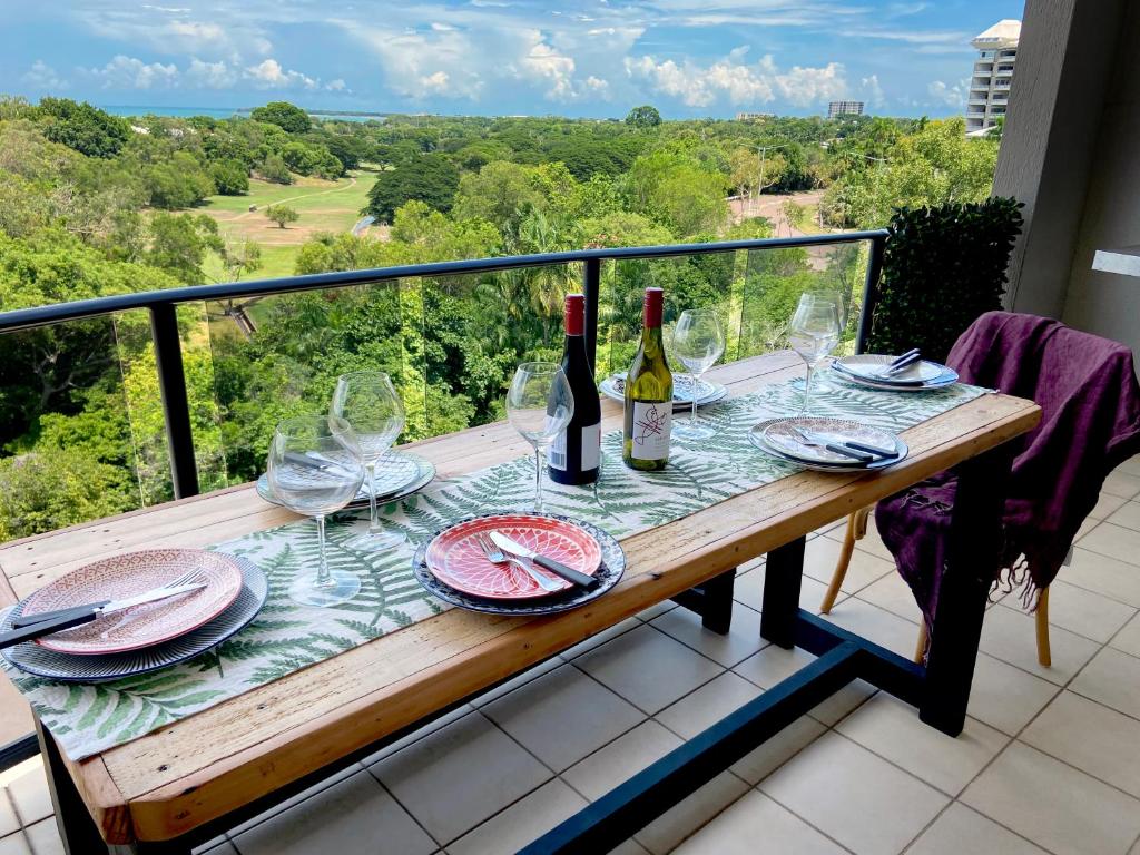 einen Tisch mit Weinflaschen und Gläsern auf dem Balkon in der Unterkunft Beautiful spacious city apartment with views out to the Arafura Sea in Darwin