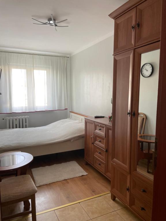 1 dormitorio con 1 cama, armario y reloj en Apartament w centrum, en Żagań