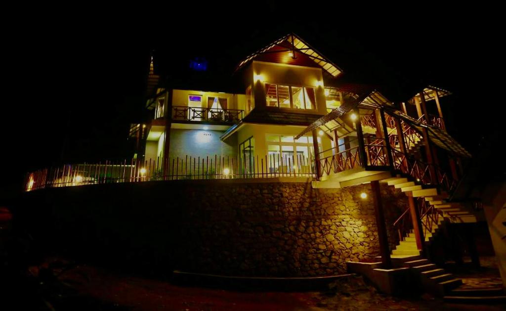 uma casa grande com luzes acesas à noite em The RaaRees Resort - A Hidden Resort in Munnar em Munnar