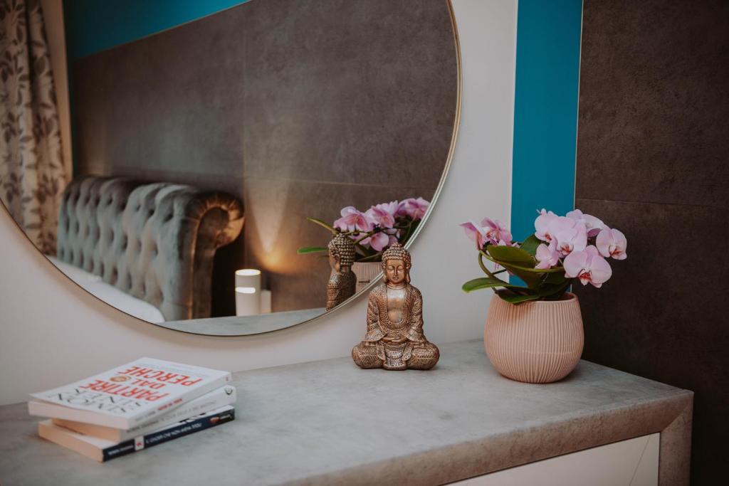 a table with a mirror and a vase with pink flowers at La Luce di Sirmione in Sirmione