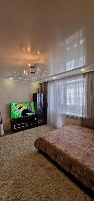 Апартаменты на СОВЕТСКОЙ 39 في بتروبافلوفسك: غرفة معيشة مع سرير وتلفزيون بشاشة مسطحة