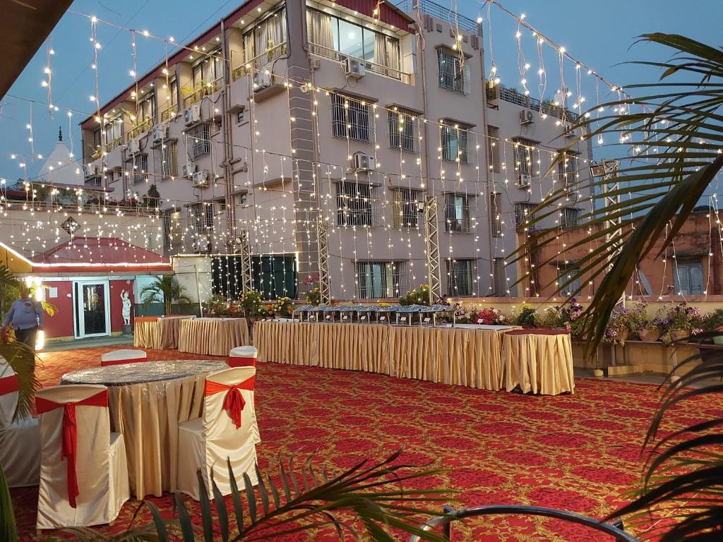 a banquet hall with tables and lights in front of a building at HOTEL INDRAPRASTHA in Māldah