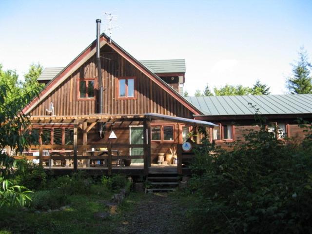 une grande maison en bois avec un toit en gambrel dans l'établissement Toipirka Kitaobihiro Youth Hostel, à Otofuke