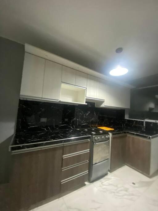 een keuken met zwarte aanrechtbladen en witte kasten bij Departamento centrico in Ilo