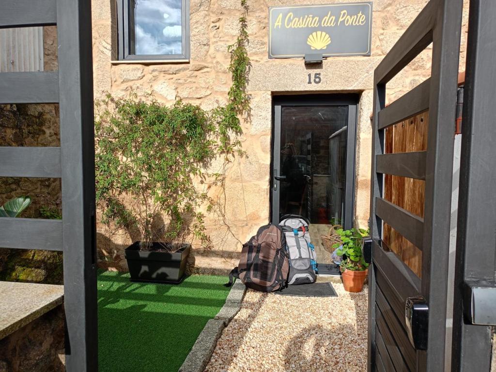 an open door to a building with a backpack on the grass at A Casiña da Ponte in Padrón