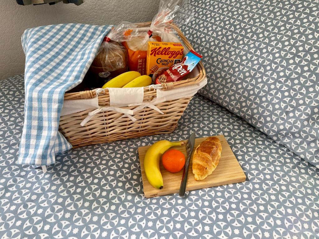 a basket of fruit and bread on a bed at Seaside Homestay - Ensuite twin room with Kitchenette in Paignton
