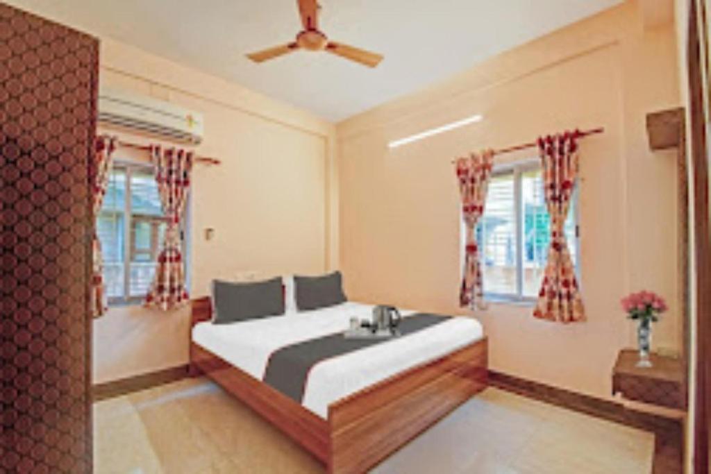 a bedroom with a bed and two windows at Arhan Villa Inn Kolkata in Thākurdwari