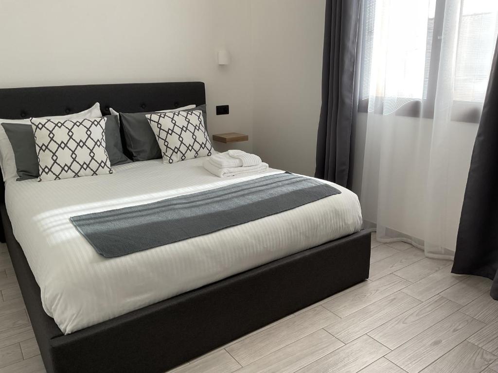 1 dormitorio con 1 cama grande con almohadas blancas y negras en Climy en Sestu