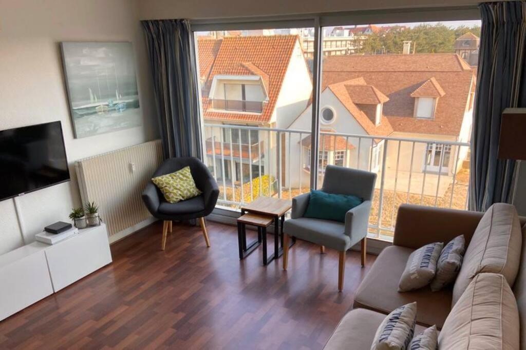 un salon avec un canapé et des chaises et une grande fenêtre dans l'établissement Appartement 2 chambres proche mer & centre-ville av wifi, à Le Touquet-Paris-Plage