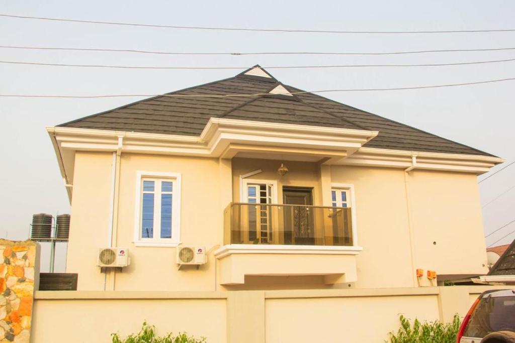 a small yellow house with a black roof at 3Tee Serviced Apartment Abeokuta in Abeokuta