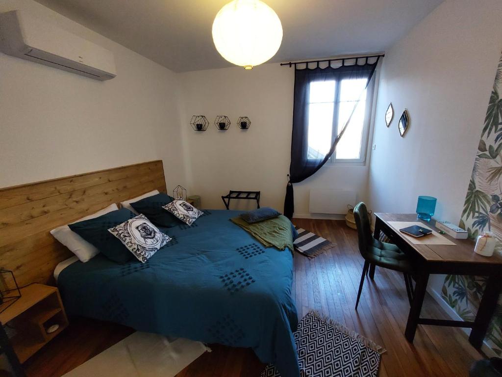 - une chambre avec un lit bleu, un bureau et une fenêtre dans l'établissement Les Minimes, à Issoudun