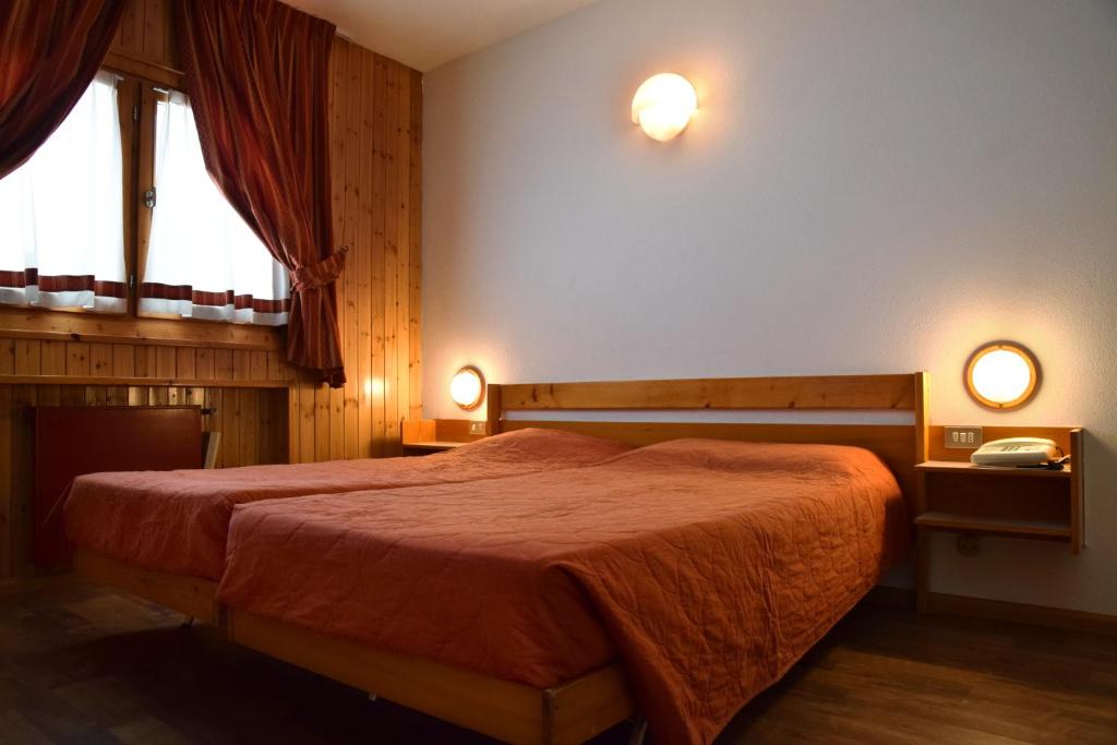 sypialnia z łóżkiem i 2 lampkami na ścianie w obiekcie Hostel San Matteo w mieście Santa Caterina Valfurva