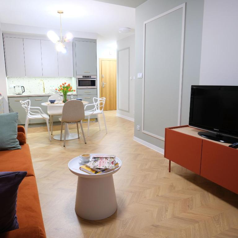 ein Wohnzimmer mit einem Sofa, einem TV und einem Tisch in der Unterkunft Apartament Andersa Biłgoraj parking podziemny in Biłgoraj