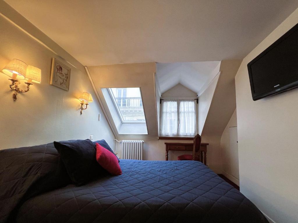 a bedroom with a bed with a blue blanket and a window at Hôtel La Sanguine in Paris