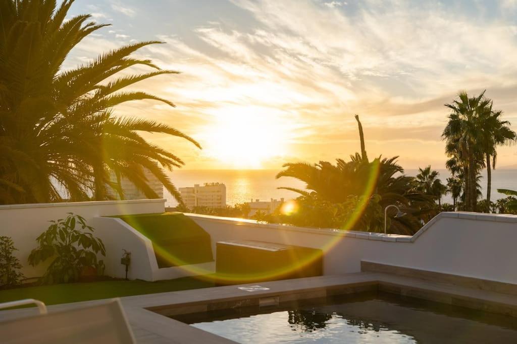 a villa with a swimming pool and a sunset at Moderní vila s bazénem in Adeje