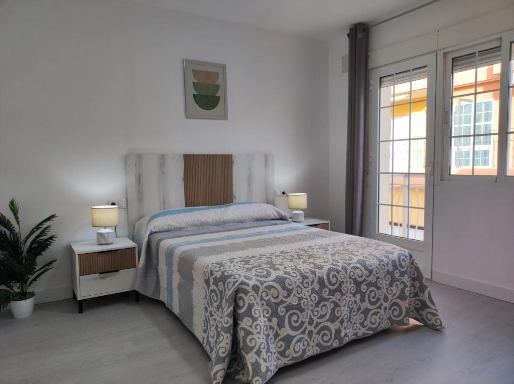 ein Schlafzimmer mit einem Bett, zwei Lampen und zwei Fenstern in der Unterkunft Apartamentos Costa II in Los Alcázares
