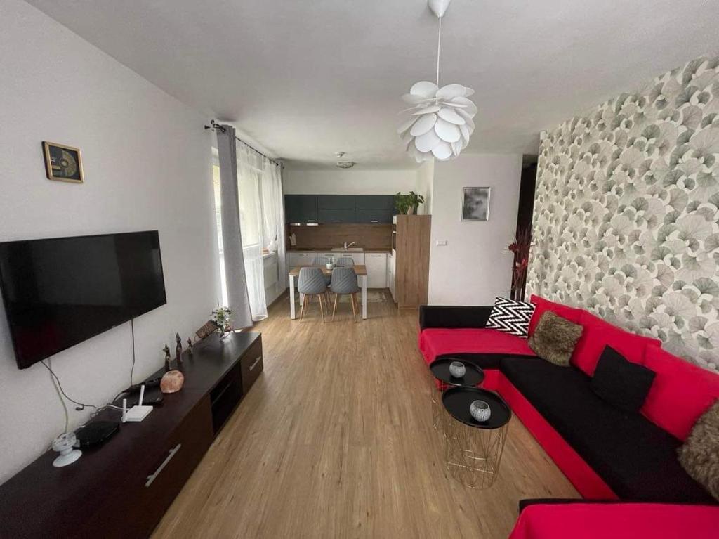 a living room with a red couch and a flat screen tv at Apartmán pod Kalváriou in Oščadnica