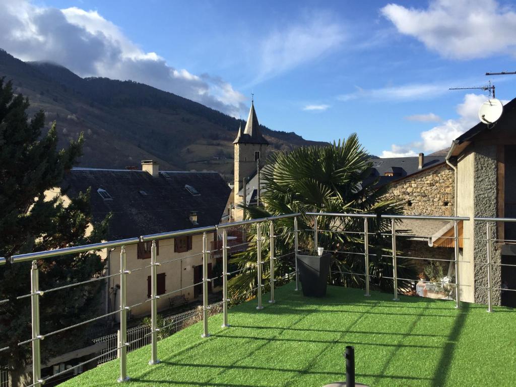 uma varanda com relva verde e uma igreja em Maison au calme vue sur les montagnes em Asté
