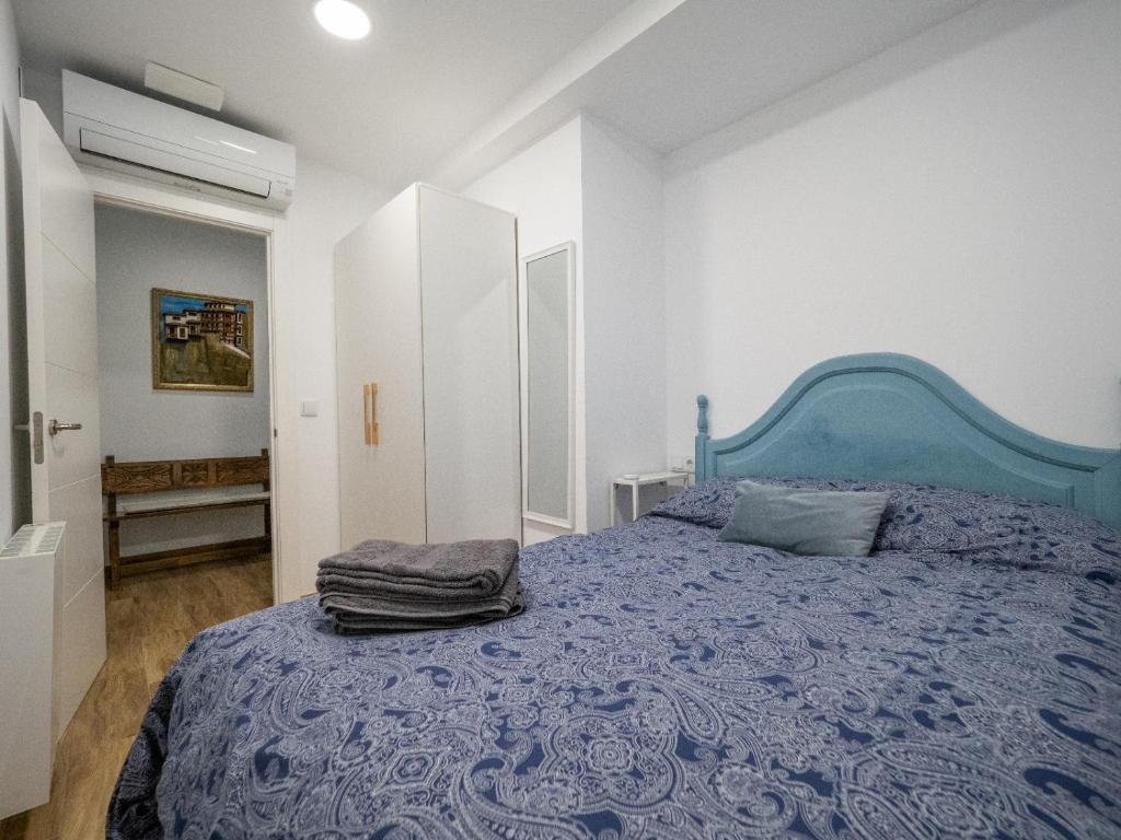 1 dormitorio con 1 cama azul en una habitación blanca en Los Carros, en Cuenca