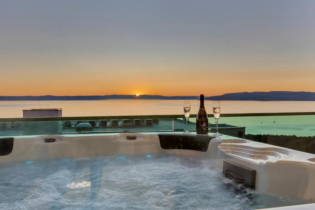 a hot tub with a bottle of wine and wine glasses at Exclusive Penthouse Big Blue with private Jacuzzi in Makarska