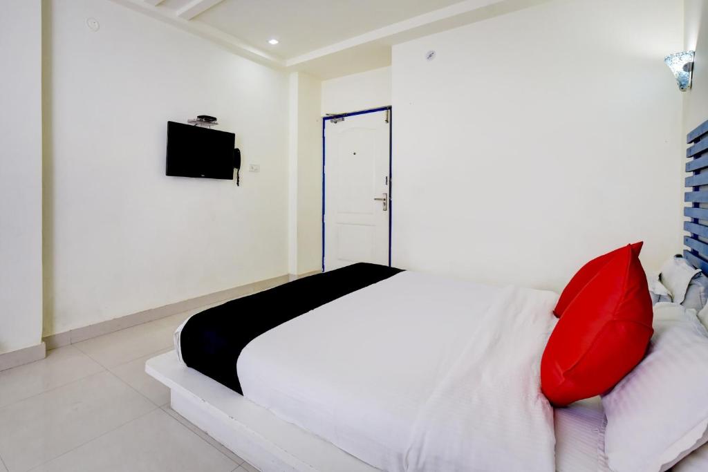 een slaapkamer met een wit bed en een rood kussen bij Collection O CORACAO HOTEL in Jaipur