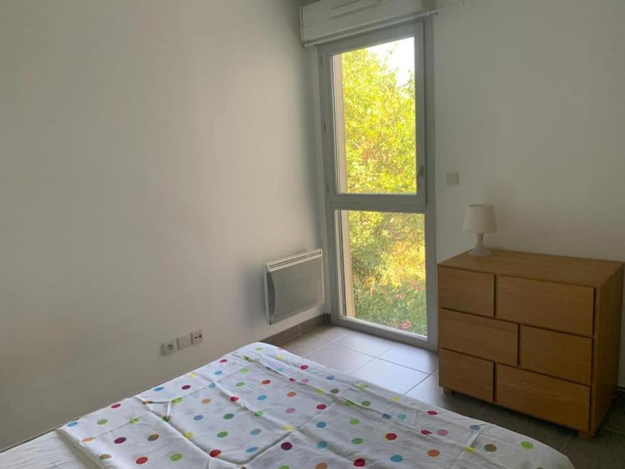 - une chambre avec un lit, une fenêtre et une commode dans l'établissement Joli T2 avec terrasse au calme, à Montpellier