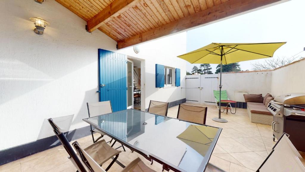 ブルティニョール・シュル・メールにあるLa Villa Bleu 300 m de la Merのガラスのテーブルと黄色い傘のあるダイニングルーム