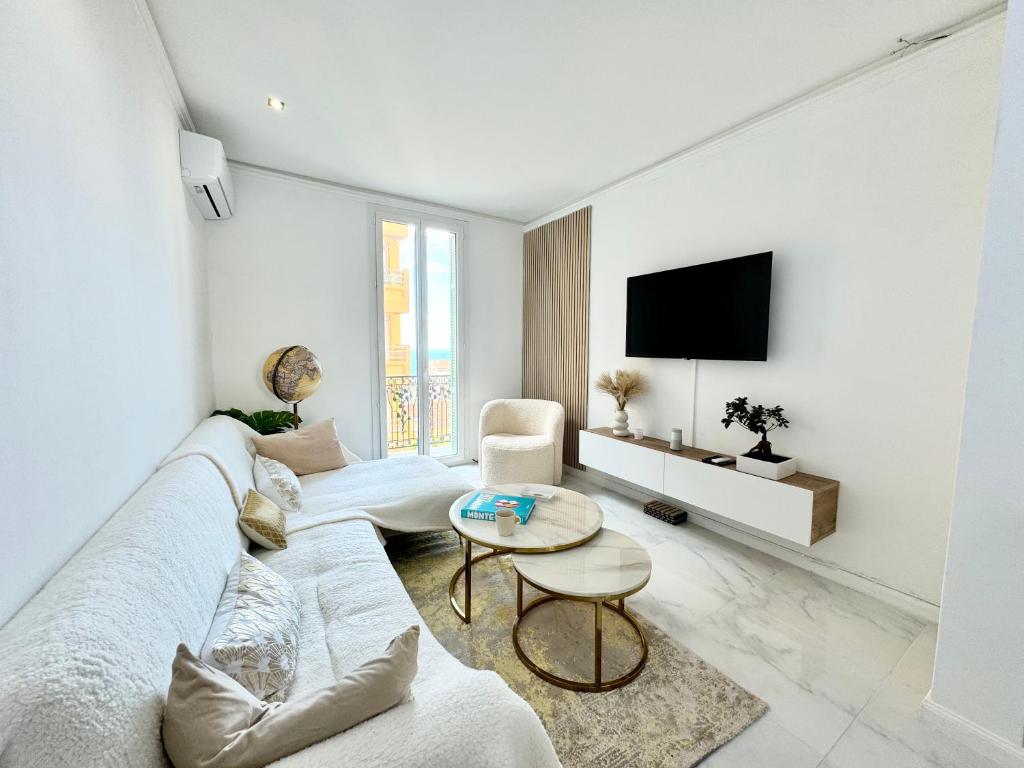 Il comprend un salon blanc doté d'un canapé et d'une télévision. dans l'établissement Appartement vue mer vue Monaco, à Beausoleil