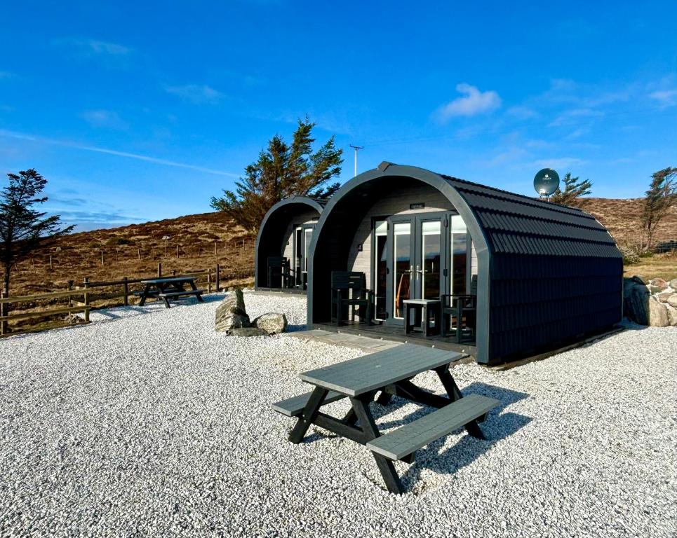 a black building with a bench in front of it at Stoer Pods - Quinag Pod in Lochinver