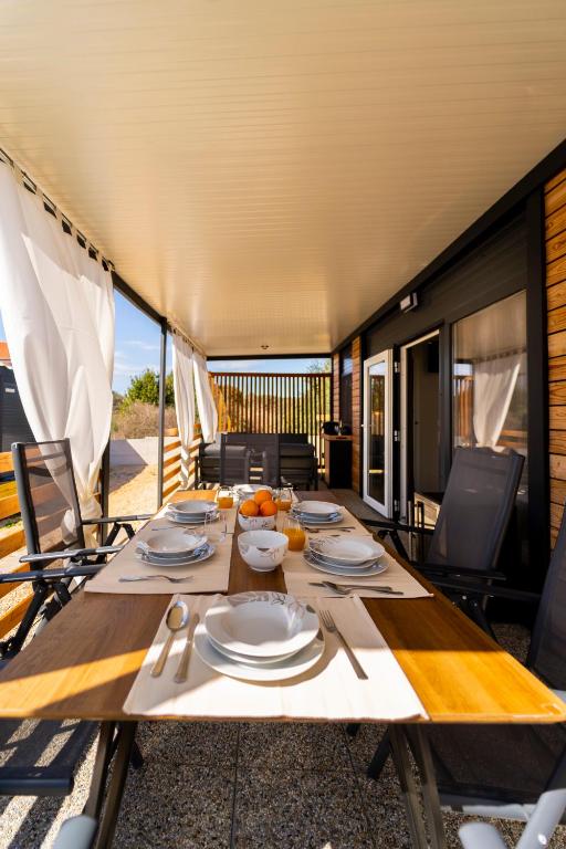 a dining table with plates and utensils on top at Mobile home Mariola in Sveti Petar