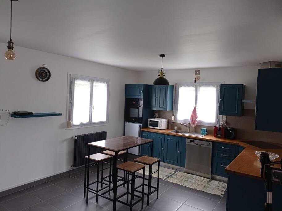 une cuisine avec des armoires bleues et une table et des chaises dans l'établissement Maison de vacances Morbihan, à Landaul