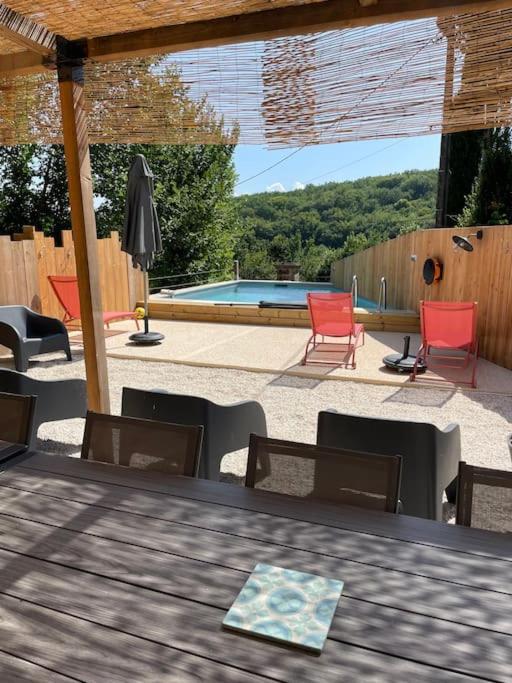 un patio avec une table et des chaises et une piscine dans l'établissement Maison Vacances 12 pers / Périgord Noir / Piscine, à Saint-Julien-de-Lampon