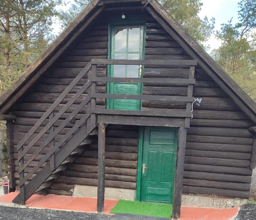 drewniany domek z zielonymi drzwiami i schodami w obiekcie Brvnara Gromki - Mountain house w mieście Han Pijesak