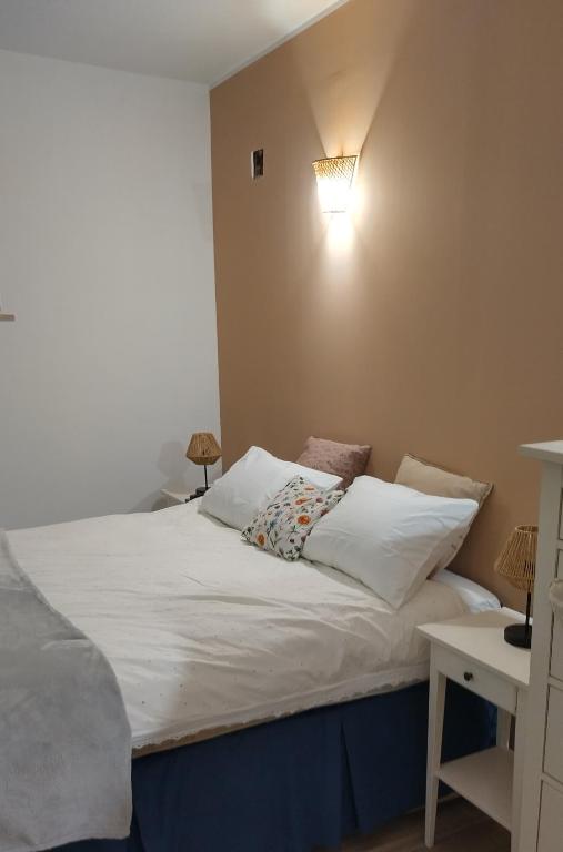 a bed with white pillows and a light on the wall at Studio Rocha Carvoeiro- Open Space in Carvoeiro