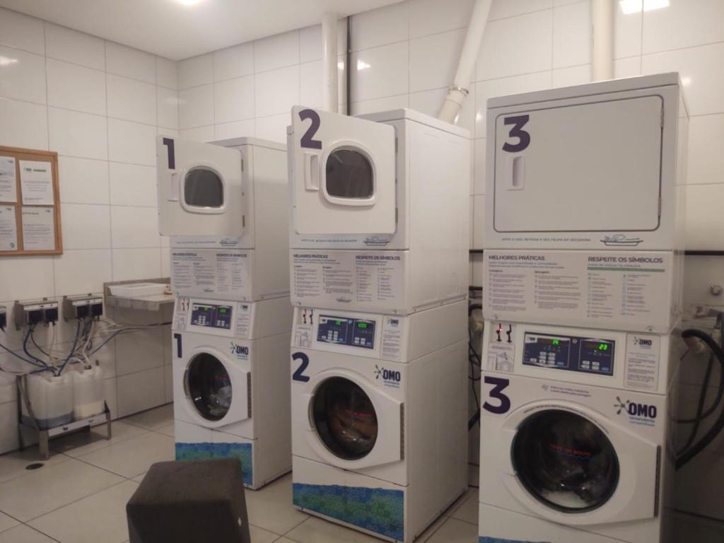 a laundry room with three machines with numbers on them at Beach Class Ilha Do Leite 3206 in Recife