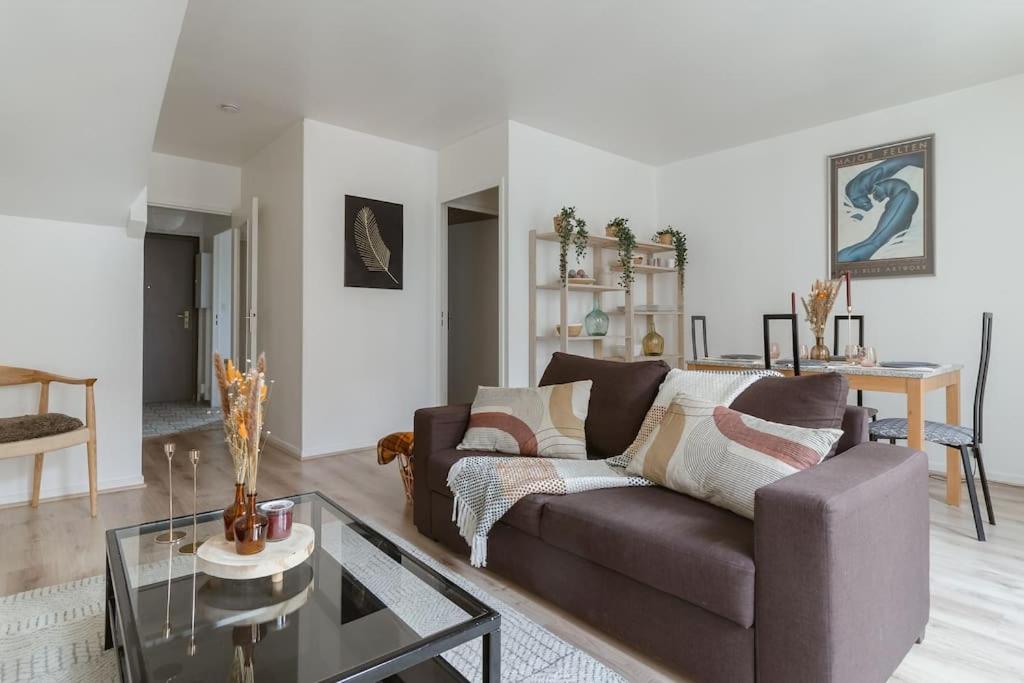 un salon avec un canapé et une table en verre dans l'établissement Beau T3 à quelques minutes des sites Olympiques, à Montigny-le-Bretonneux