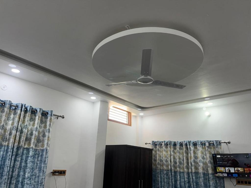 een plafondventilator in een kamer met gordijnen bij Shri Ram International Home Stay Ayodhya in Ayodhya