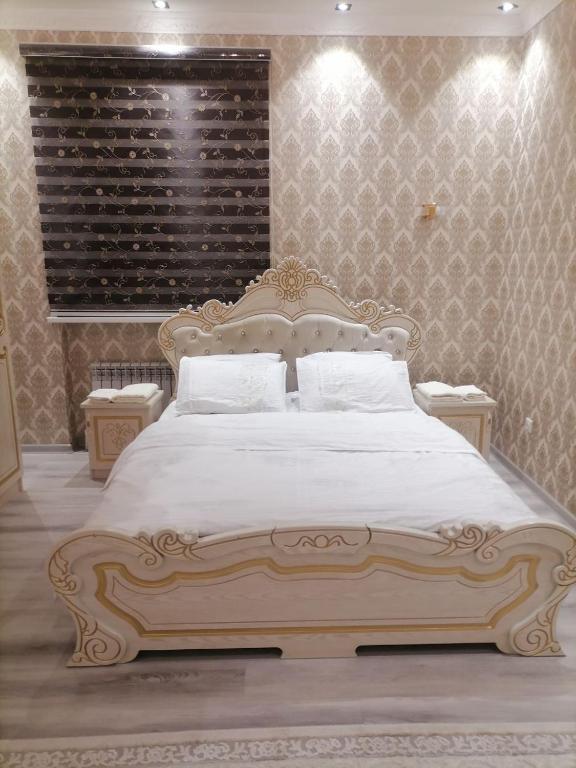 1 dormitorio con 1 cama grande con sábanas blancas en Rudakiy Apartment, en Samarkand