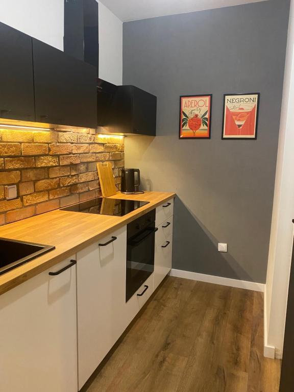 een keuken met witte kasten en een bakstenen muur bij Chillout Loft Apartment AL20 in Warschau