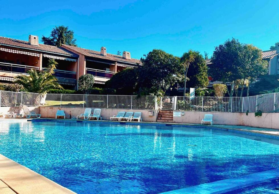 une grande piscine bleue avec des chaises en face d'un bâtiment dans l'établissement Appartement T3 • Plage à 300m • Les Oursinières, au Pradet