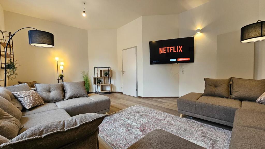 un soggiorno con due divani e una televisione sul muro di YFB-170m2 Apartment für bis zu 15, modern, 1min zu UBahn, Ruhige Lage, Parkplätze, WIFI, Netflix, Kindergerecht a Norimberga